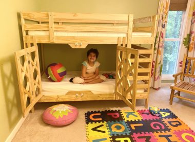 DIY projects and special needs products | Angelman Syndrome News | Juliana, 11, who has Angelman, sits cross-legged in a safety bunk bed her parents built. A natural wood color, the bed has two safety gates and a ladder, and sits in a colorful bedroom.