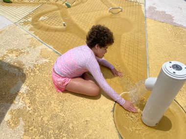 regression \ Angelman Syndrome News \ Juliana, 11, loves playing with water. Here she sits outdoors in a bright pink shirt and plays with water flowing from a large sprayer