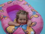 Juliana, pictured here as a toddler, smiles from a pink inflatable float with orange butterflies.