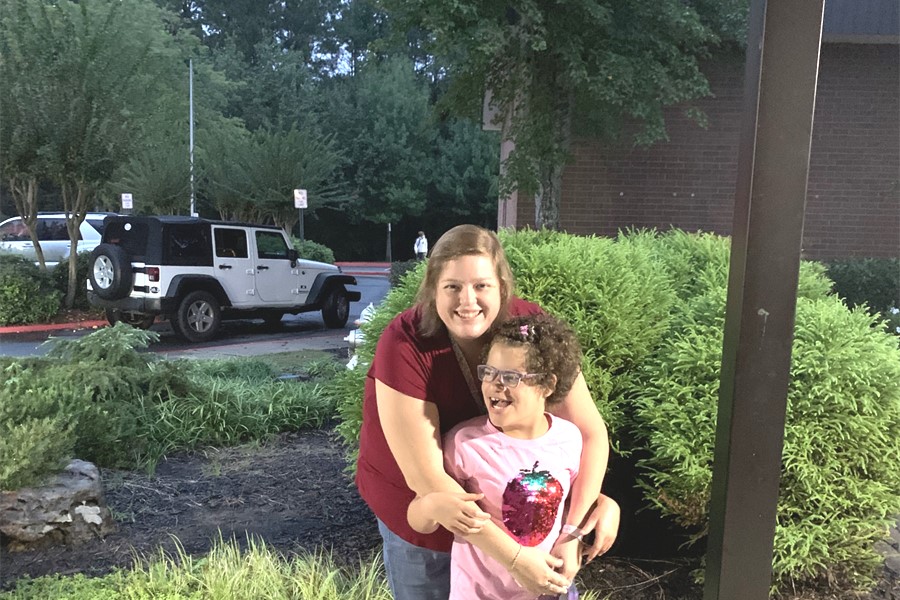 preparing Angelman child for school | Angelman Syndrome News | Juliana smiles as she receives an embrace from her teacher