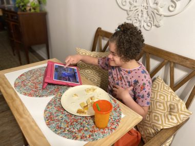 Angelman and hospitalization | Angelman Syndrome News | Juliana eats breakfast while playing with her iPad, dressed in a pinkish robe she received during her first hospitalization a decade ago.