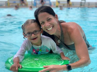Een vrouw houdt haar 8-jarige dochter vast in een zwembad. 